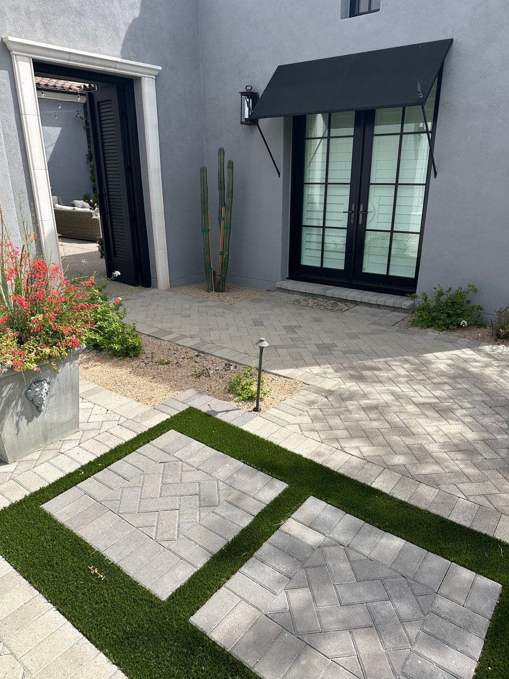 Modern outdoor pathway featuring paver stones and artificial grass alongside a stylish entrance.
