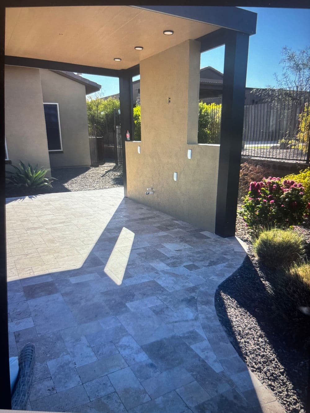 Modern patio featuring stone pavers, lush landscaping, and sleek overhead lighting.