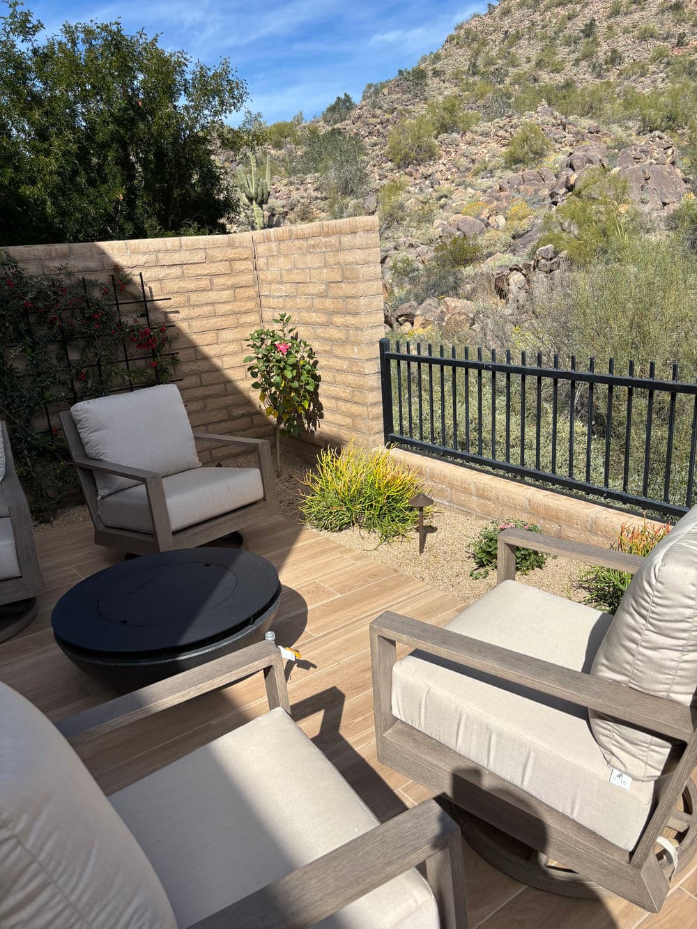 Cozy patio seating with mountain views, surrounded by lush greenery and a stone wall.