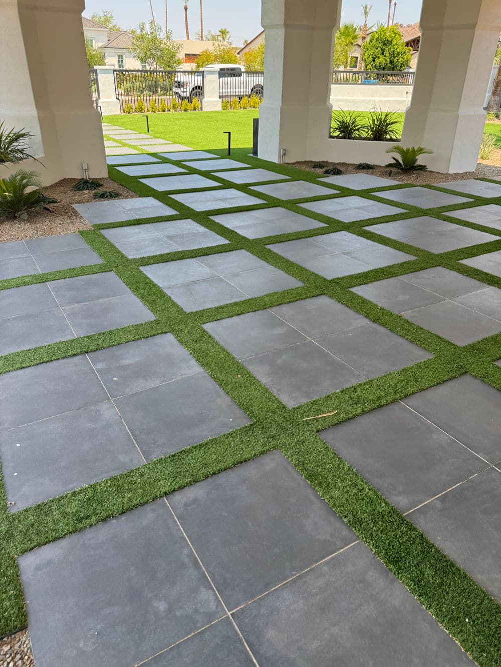 Modern patio design featuring grey stone pavers and green grass in a landscaped area.