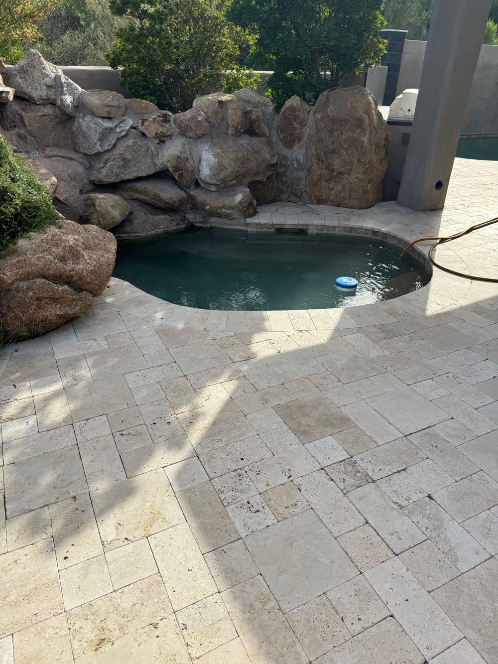 Backyard pool surrounded by natural stone features and elegant paver patio.
