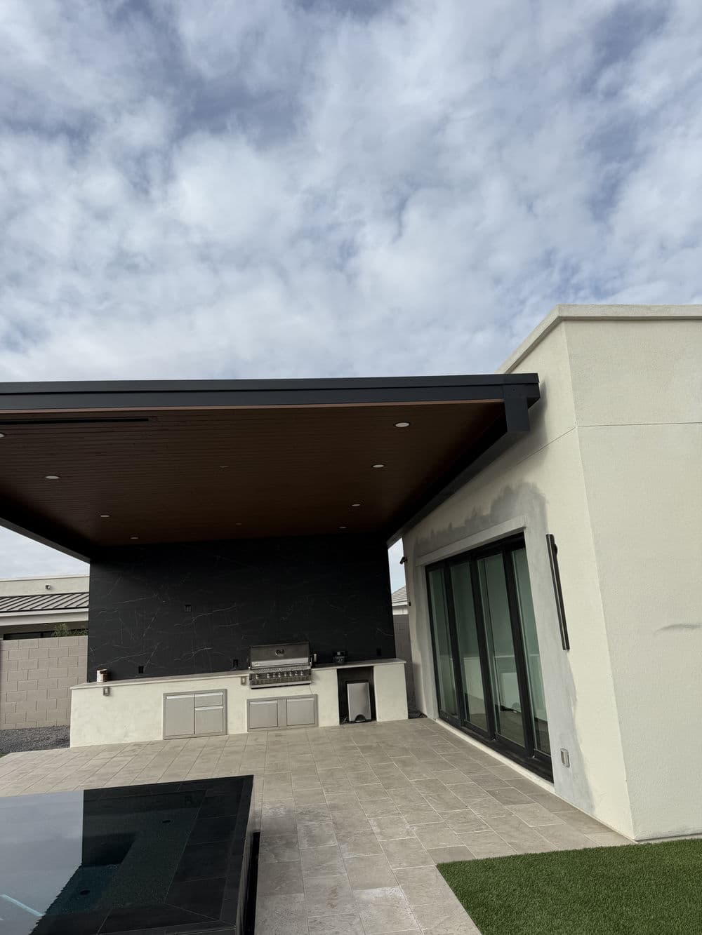 Modern outdoor kitchen with grill and sleek design under a cloudy sky.