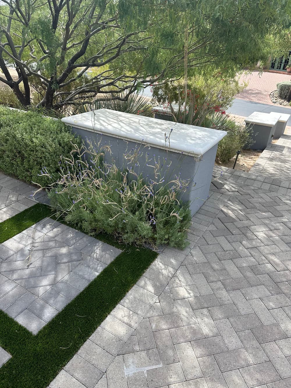 Landscape view featuring a manicured garden with shrubs, stones, and artificial grass.