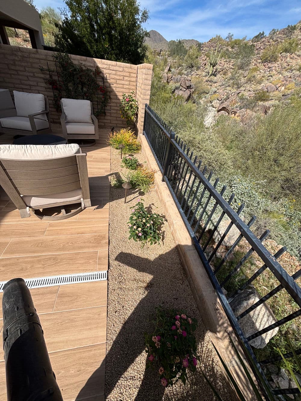 Modern patio with seating, desert landscaping, and mountain view under clear blue sky.