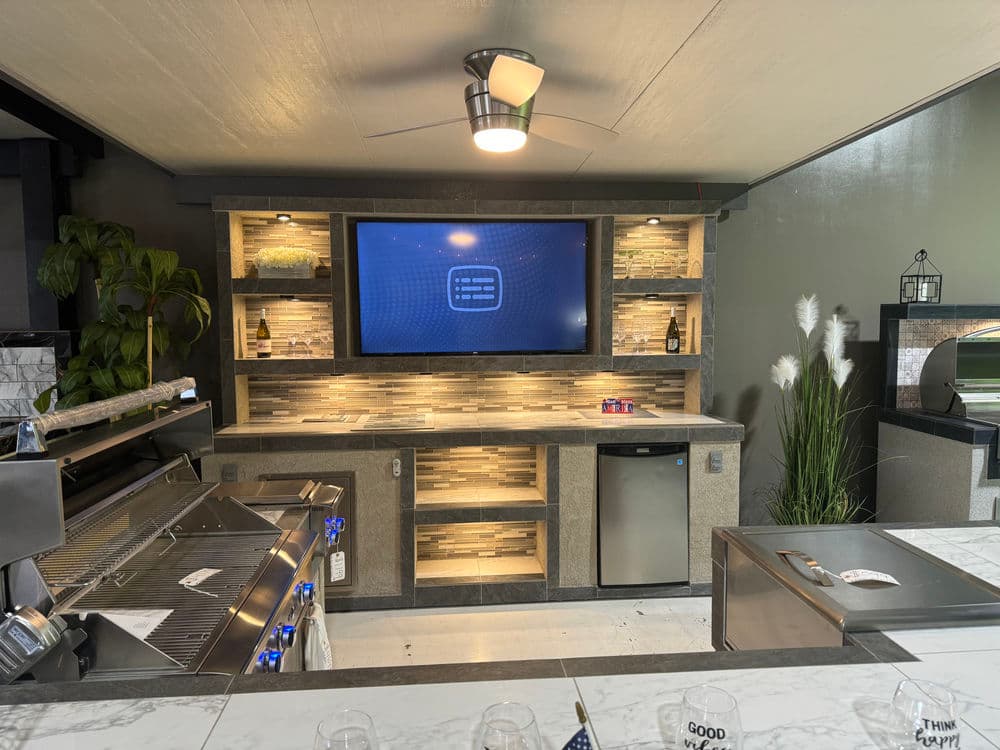 Modern kitchen setup featuring a sleek bar area, TV, stainless steel appliances, and stylish decor.
