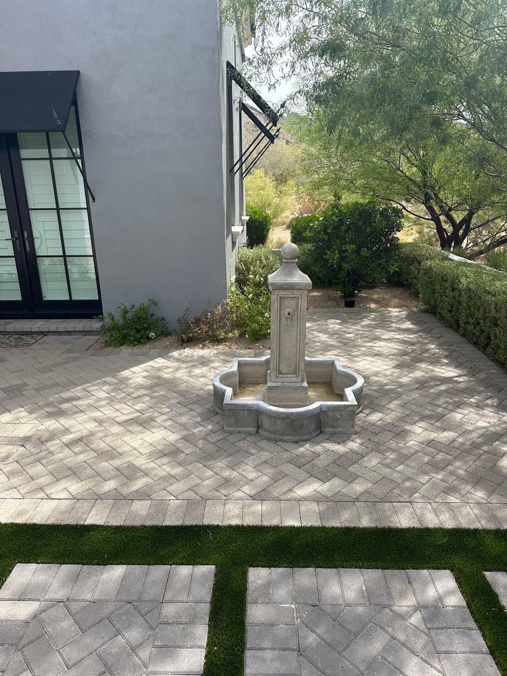 Stylish outdoor fountain in a landscaped courtyard with paver stones and greenery.