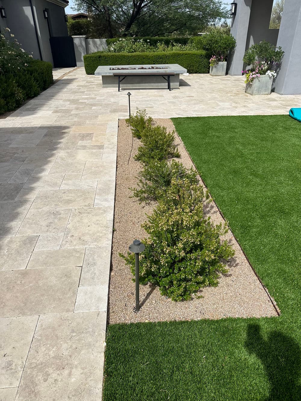 Modern landscape design featuring a stone pathway, greenery, and decorative planters.