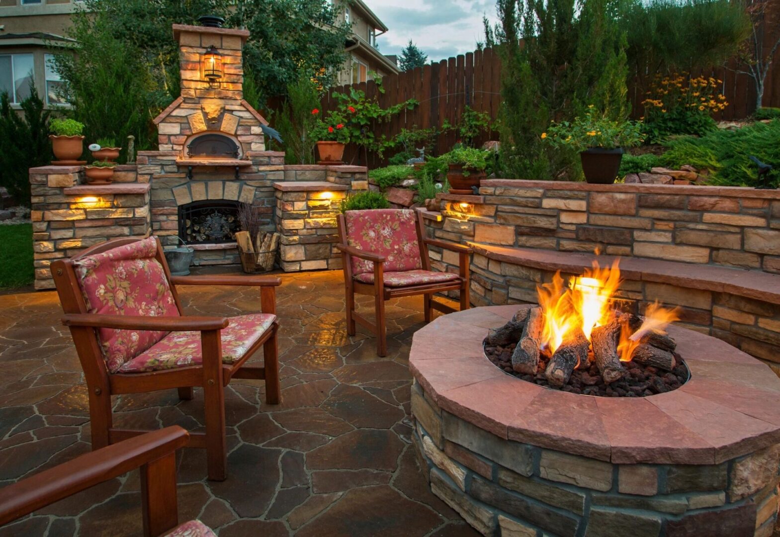 A fire pit with chairs around it and trees in the background.